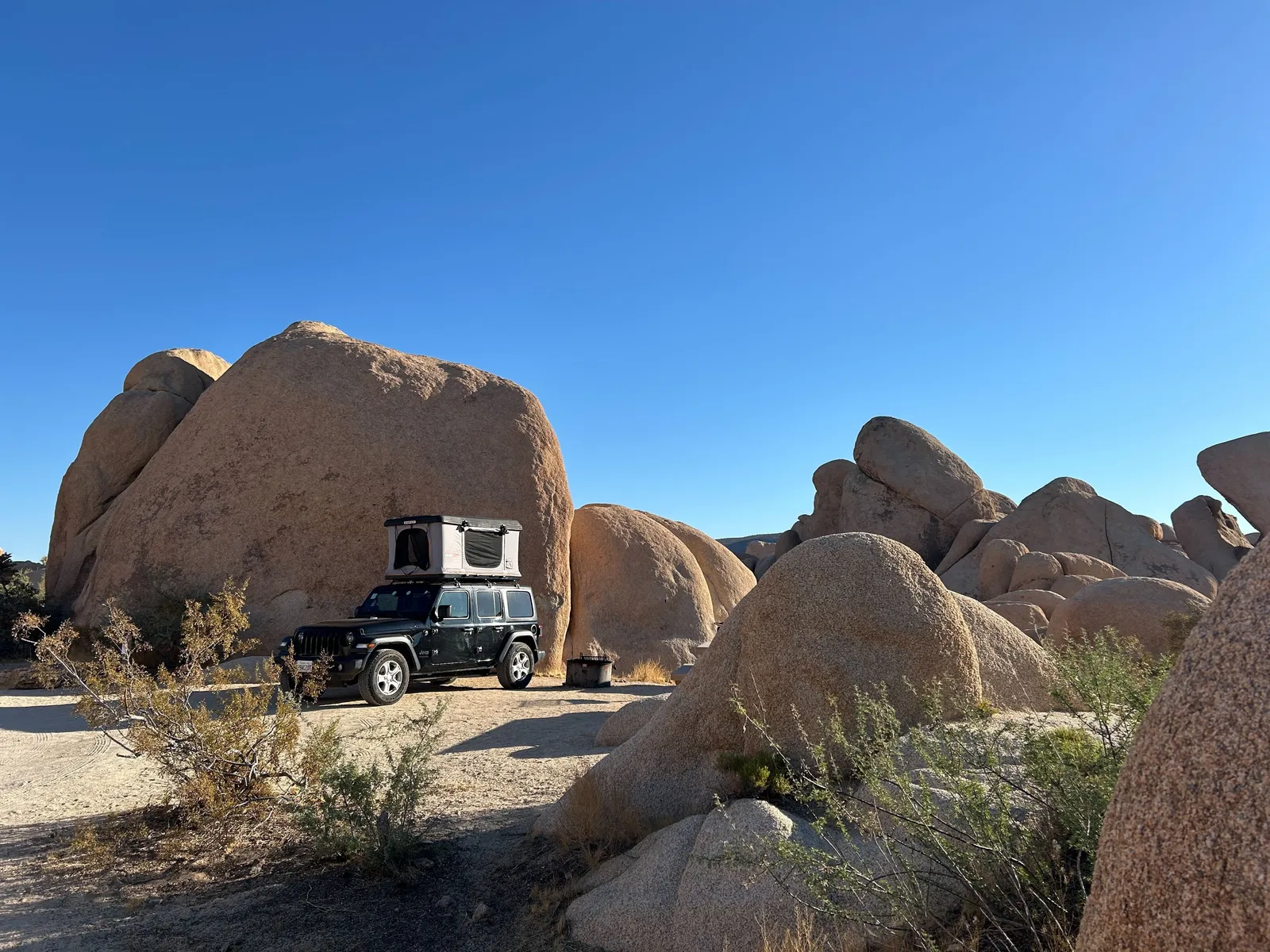 Ein Jeep mit Dachzelt vor grossen Felsen.