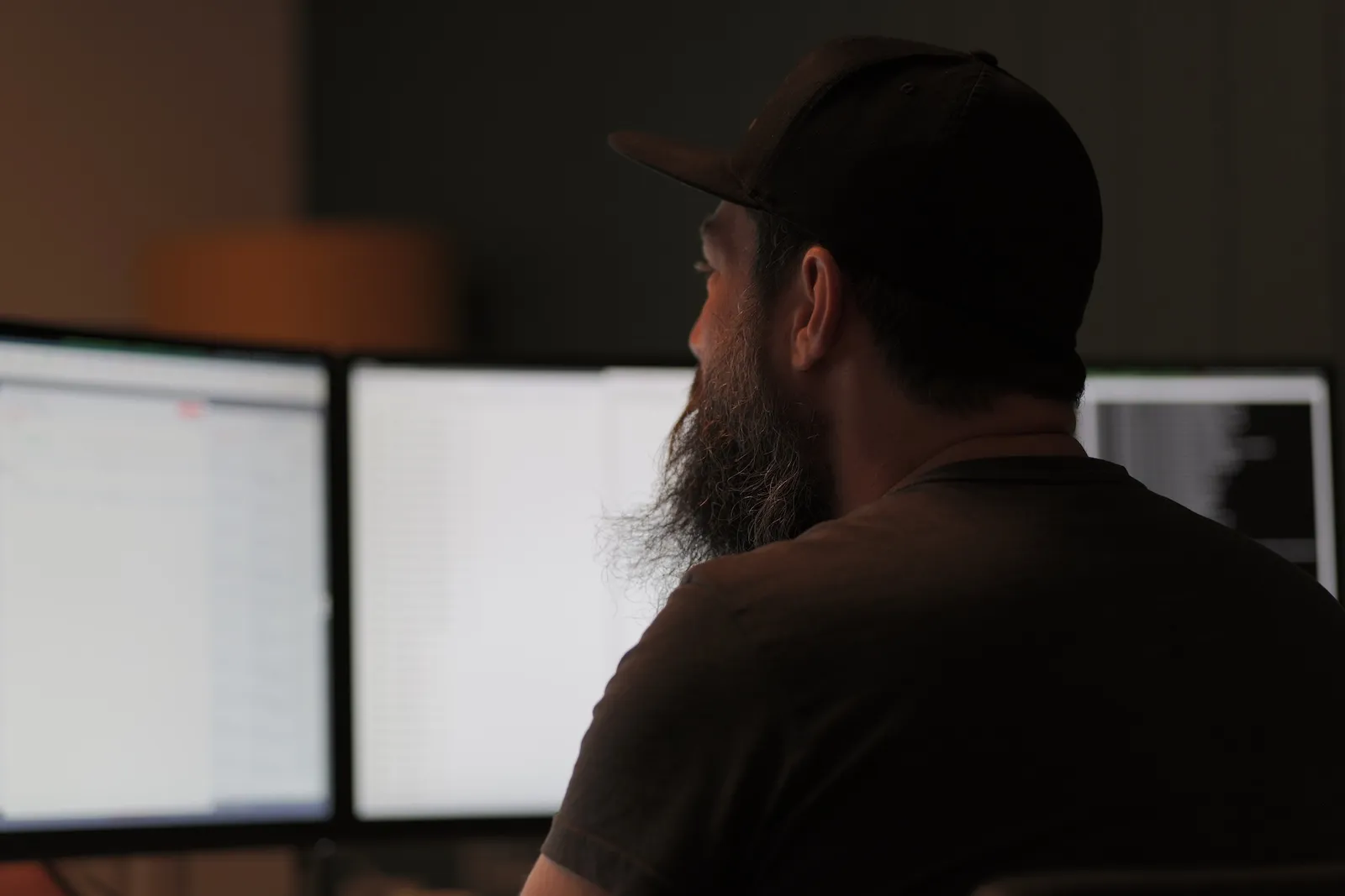 Andri an seinem Arbeitsplatz im Ops One Büro, im Hintergrund zwei Bildschirme.