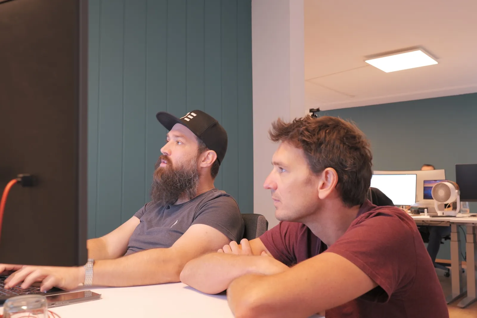 Andri und Martin im Ops One Büro an Andris Arbeitsplatz, schauen gemeinsam auf den Bildschirm.